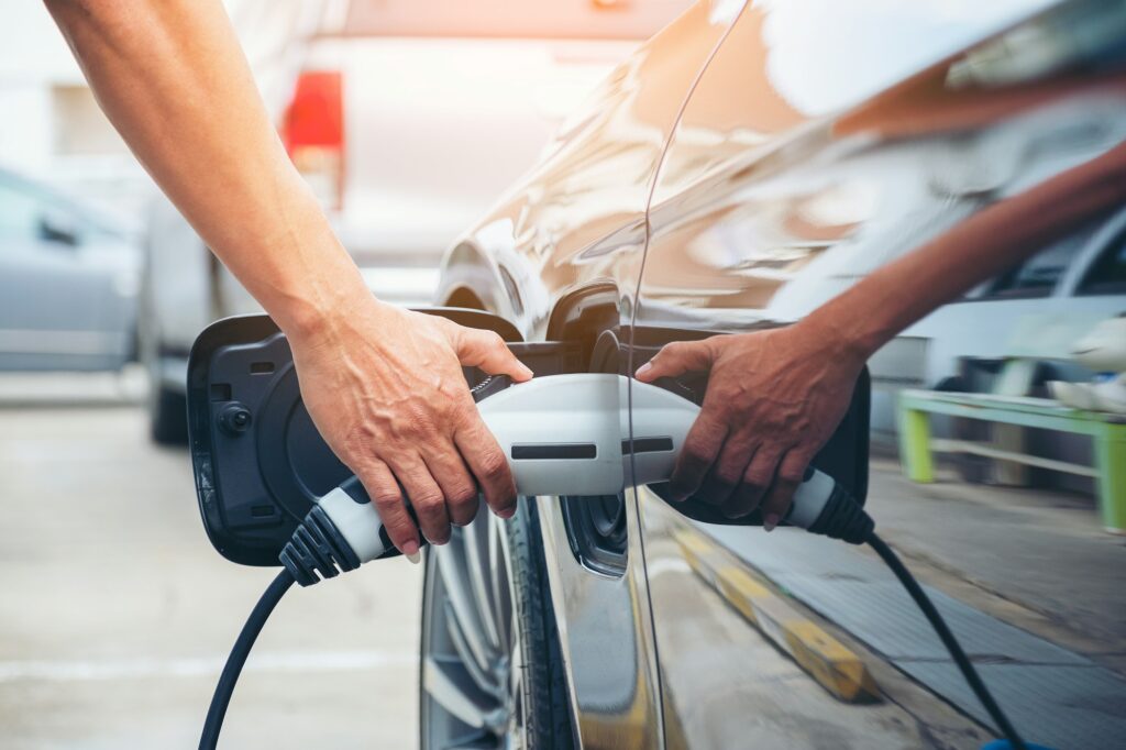 Hand hold of charging modern electric car battery on the street which are the future